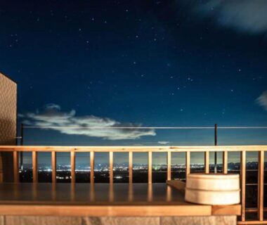 Night balcony with wooden soaking tub and railing overlooking city lights and stars at Wakaki Ryokan, Nasu Yumoto Onsen