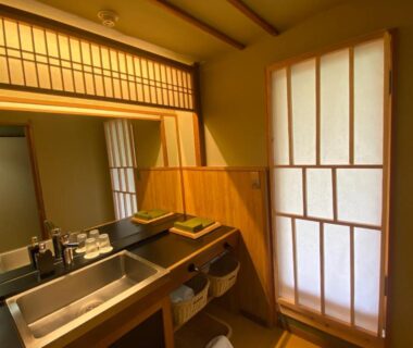 Washbasin and mirror with wooden counter, shoji screen and wooden floor in a ryokan room in Kanagawa