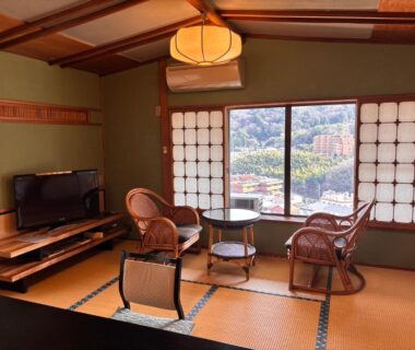 Tatami room with low table, rattan chairs and shoji windows overlooking hillside view in Kanagawa