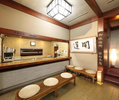Wooden reception with round cushion bench seating, calligraphy panel and staircase at Wakamatsu Honten, Chiba, Kantō