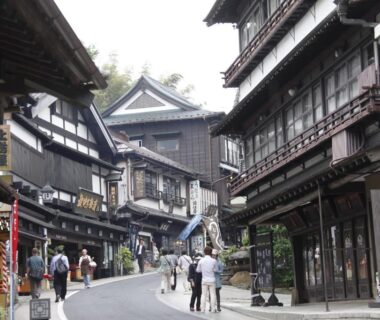 Traditional wooden storefronts lining a sloped street by Wakamatsu Honten in Chiba Kantō region