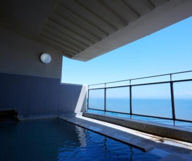 Outdoor onsen bath at Wakamatsu Hot Spring Resort with glass railing and ocean view in Hokkaido
