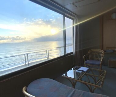 Seating area with low table and chairs overlooking the sea through a large window at Wakamatsu, Hokkaidō