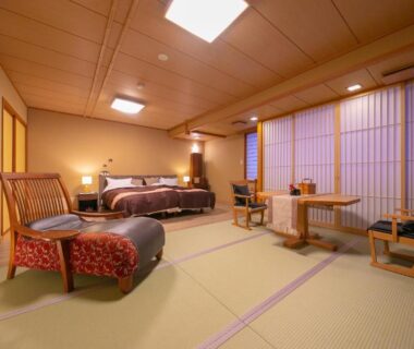 Spacious tatami room with Western beds, shoji screens, low table and wooden ceiling at Wakamatsuya, Yamagata