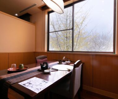 Window-side dining area with wooden table, chairs and tea set at Wakamatsuya in Yamagata