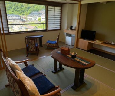 Tatami sitting room with low table and chairs, Wakamatsuya ryokan overlooking Yamagata town and surrounding hills