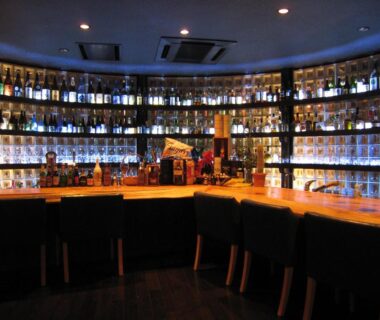 Wooden bar counter with stools and bottle-lined shelves at Wakamizusou, Yamanashi, Chūbu