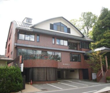 Brick exterior of Wakamizusou with covered parking and hillside greenery in Yamanashi, Chūbu