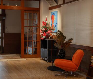 Lobby with orange lounge chair, wooden flooring, shoji screens and floral display at Wakata Lodge Hakuba, Nagano