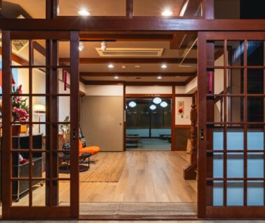 Interior entrance with wooden sliding doors, reception seating and warm lighting at Wakata Lodge Hakuba, Nagano