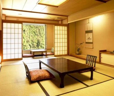 Traditional tatami room with low table, zabuton cushion, shoji screens and green hillside view at Wakatake Niigata