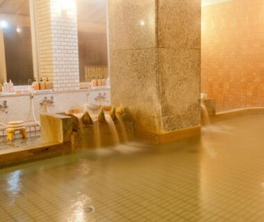 Tiled indoor onsen with cascading spouts and washing stations at Kada Kaigetsu in Wakayama