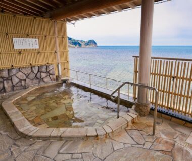 Stone onsen bath with bamboo screens and sea view at Wakayama Kada Kaigetsu
