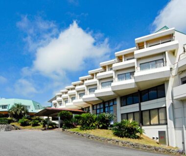 Stepped white ryokan facade with balconies under a blue sky in Izukogen, Shizuoka