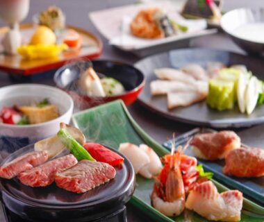 Assorted small plates with grilled meat, prawns and vegetable sides on ryokan dining table