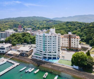 White waterfront ryokan building beside marina with moored boats, Wan Wan Paradise Toba, Mie, Japan