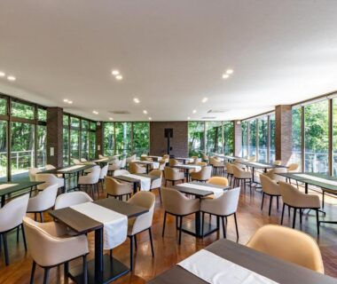 Spacious dining area with tables and large windows overlooking verdant woodland at Wan Wan Paradise Yatsugatake Yamanashi