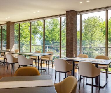 Dining area with floor-to-ceiling windows overlooking trees at Wan Wan Paradise Yatsugatake, Yamanashi