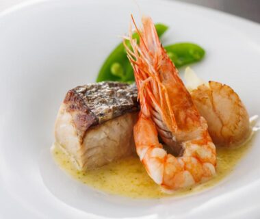 Seared fish fillet with shrimp and scallop in a light sauce, snap pea garnish