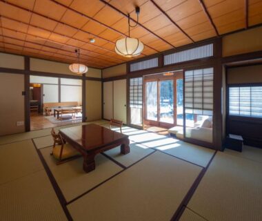 Spacious tatami room with low wooden table, shoji screens and sliding doors at Wanosato in Gifu