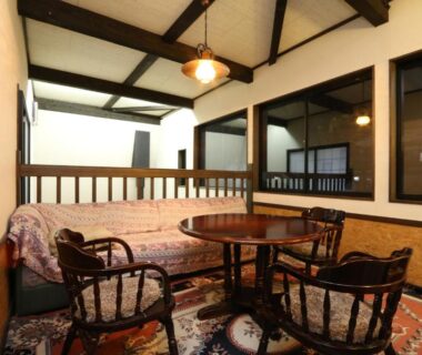 Cozy lounge with wooden chairs, round table, patterned rug and exposed beams at Warabiso, Niigata