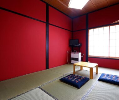 Tatami room with red walls, low wooden table, zabuton cushions, shoji window and television