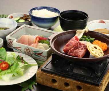 Grilled meat and assorted small dishes on tabletop stove at Warabiso, Niigata