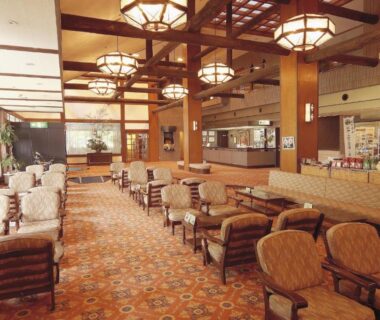 Spacious carpeted lounge with upholstered seating, wooden beams and chandeliers at Watarase Onsen Hotel Sasayuri, Wakayama
