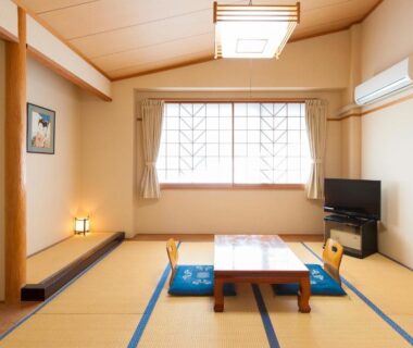 Traditional tatami room with low table, floor cushions, shoji window and television at Watarase Onsen Hotel Yamayuri Wakayama