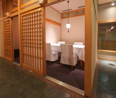 Partitioned dining alcove with white-covered chairs and wooden lattice screens at Wataya Besso Saga