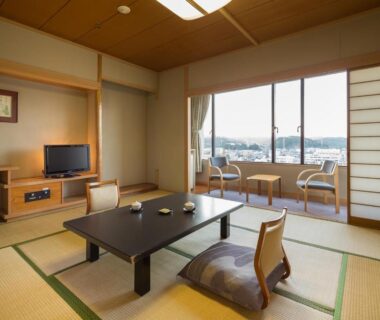 Bright tatami room with low table, cushions and sliding shoji doors overlooking town view at Wataya Besso, Saga