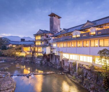 Lit riverside ryokan Wataya Besso along rocky stream in Saga, Kyūshū, Japan at dusk