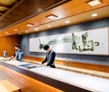 Reception desk with staff and large calligraphy art at Wataya Besso in Saga