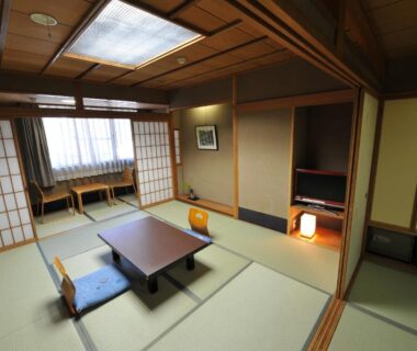 Traditional tatami room with low table, cushions, shoji screens and alcove at Watazen Ryokan in Kyoto