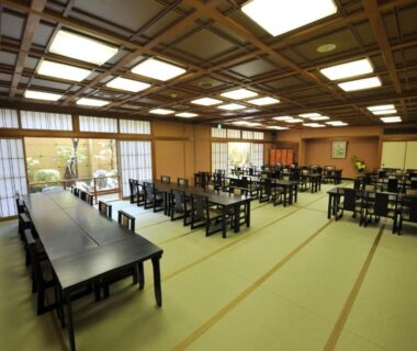 Spacious tatami dining room with low tables and shoji screens overlooking a small garden at Watazen Ryokan, Kyoto