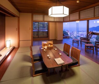 Tatami dining room with low table, window seating and city view at Watei Kazekomichi, Shizuoka