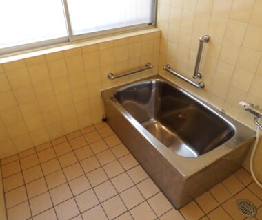 Stainless steel bathtub with shower and tiled floor in Wholeearth Ryokan Hiroshima bathroom