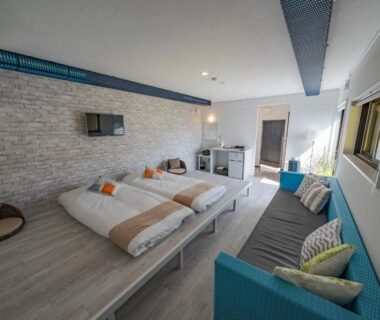 Low futon platform with sofa and wall-mounted TV at XYZ Private Spa and Seaside Resort Wakayama