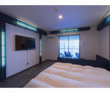 Modern guest room with two beds, wall-mounted TV and small balcony with chairs