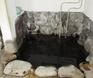 Small indoor stone onsen bath with visible pipes, YOKOSO Ryokan, Ōita