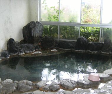 Indoor stone-edged onsen bath with steaming water at YOKOSO Ryokan in Oita, Kyūshū