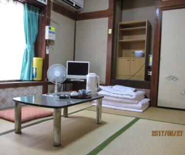 Traditional tatami room with low table and folded futon at YOKOSO Ryokan in Ōita, Kyūshū, Japan