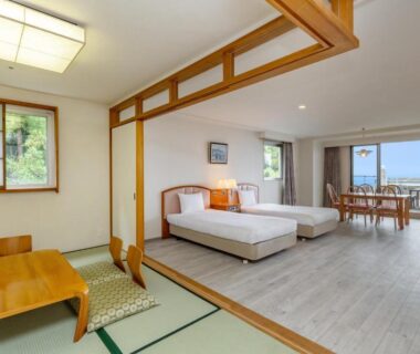 Spacious mixed Japanese-Western room with tatami area, twin beds, dining table and balcony at YU-FURI Izukogen, Shizuoka
