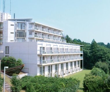 Multistory building with balconies, lawn and surrounding woodland at YU-FURI Izukogen in Shizuoka