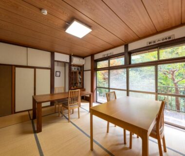 Bright tatami room with low tables, chairs and large windows overlooking greenery at YUPOPPO Hakone, Kanagawa