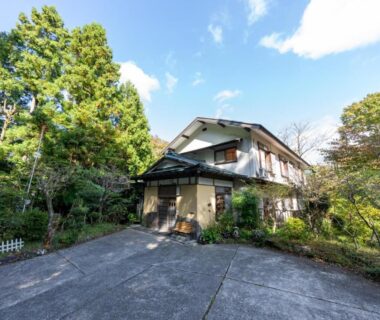 Two-story ryokan exterior with driveway and surrounding trees at YUPOPPO Hakone in Kanagawa