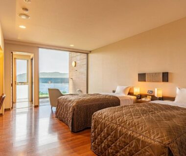 Twin bedroom with wooden floor and balcony overlooking sea at Yado Marubun, Shizuoka