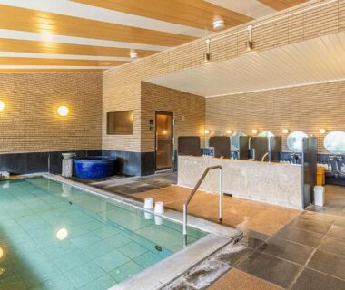 Indoor communal onsen with tiled pool, washing stations and mirrors at Yado Marubun in Shizuoka
