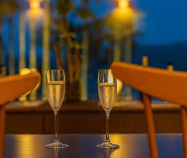Two champagne flutes on wooden table with warm lights, Yado Marubun, Shizuoka, Chūbu Japan