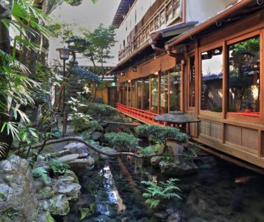 Covered wooden corridor overlooking a rock-lined stream and garden at Yadoya Kikokuso, Kyoto